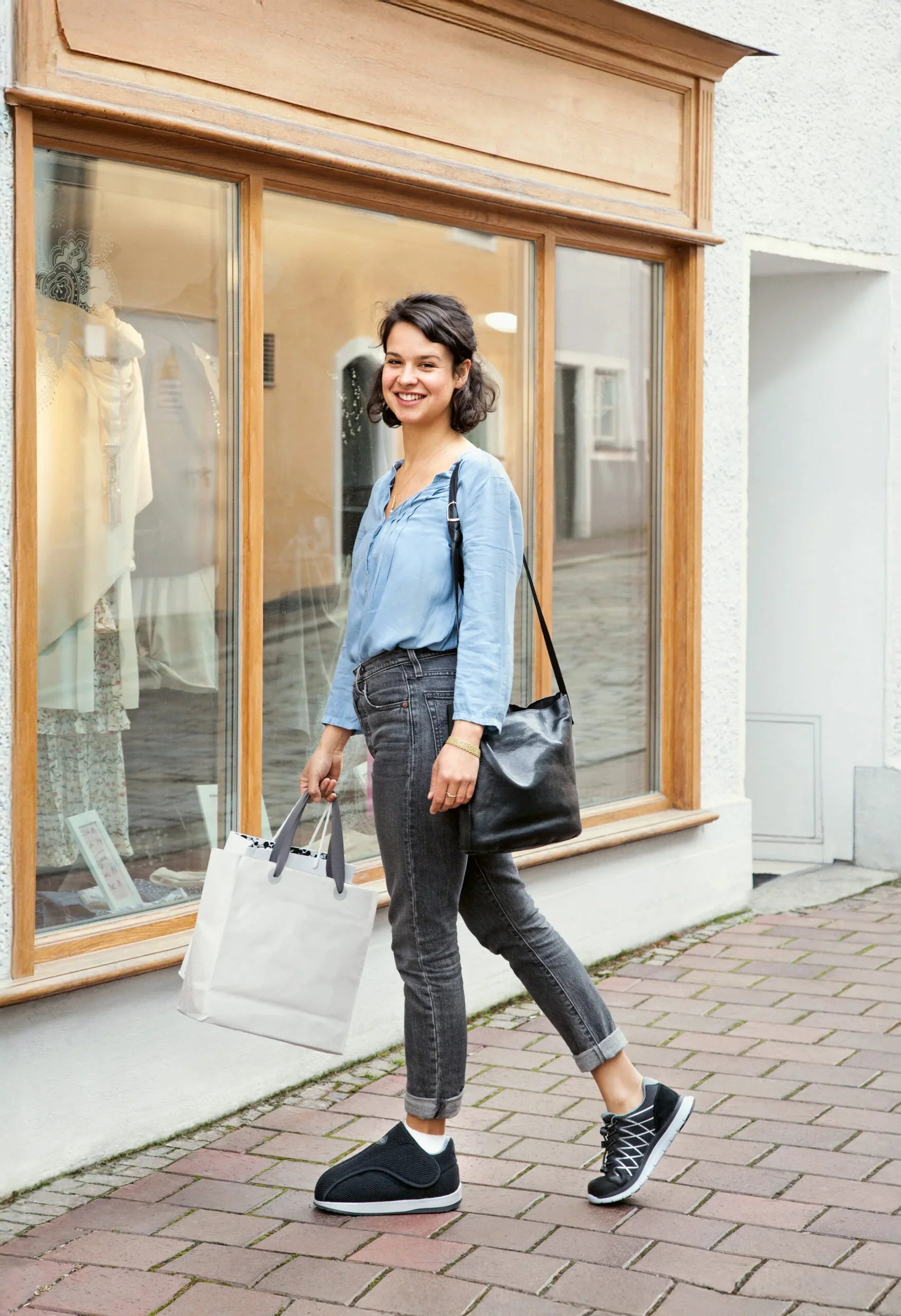 Woman walking outdoors in comfortable recovery shoes, carrying shopping bags, ideal for mobility and daily wear.